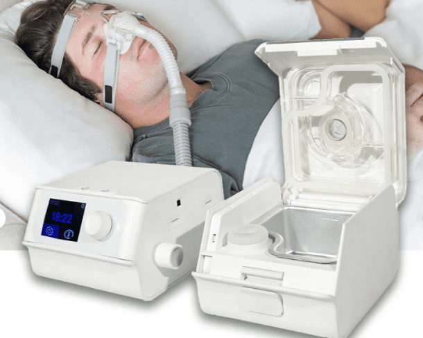 A man laying in bed with an electric cpap machine.